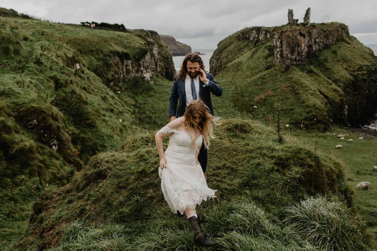 Couple eloping and walking over Irish fields with castle in the backdrop